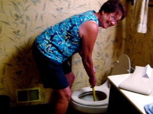 Cousin Glee unplugging toilet at the Girl Cousins' Reunion.  January is also "Someday We'll Laugh About This" month.
